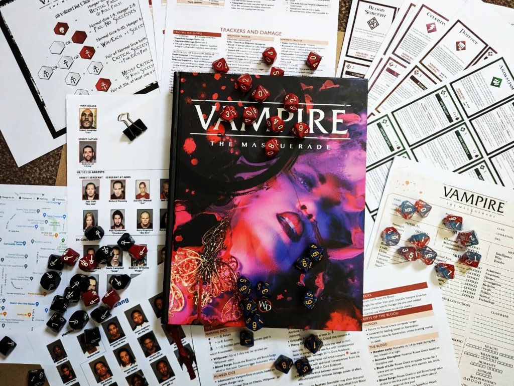 Vampire: the Masquerade V5, surrounded by dice, handouts and play paraphernalia 